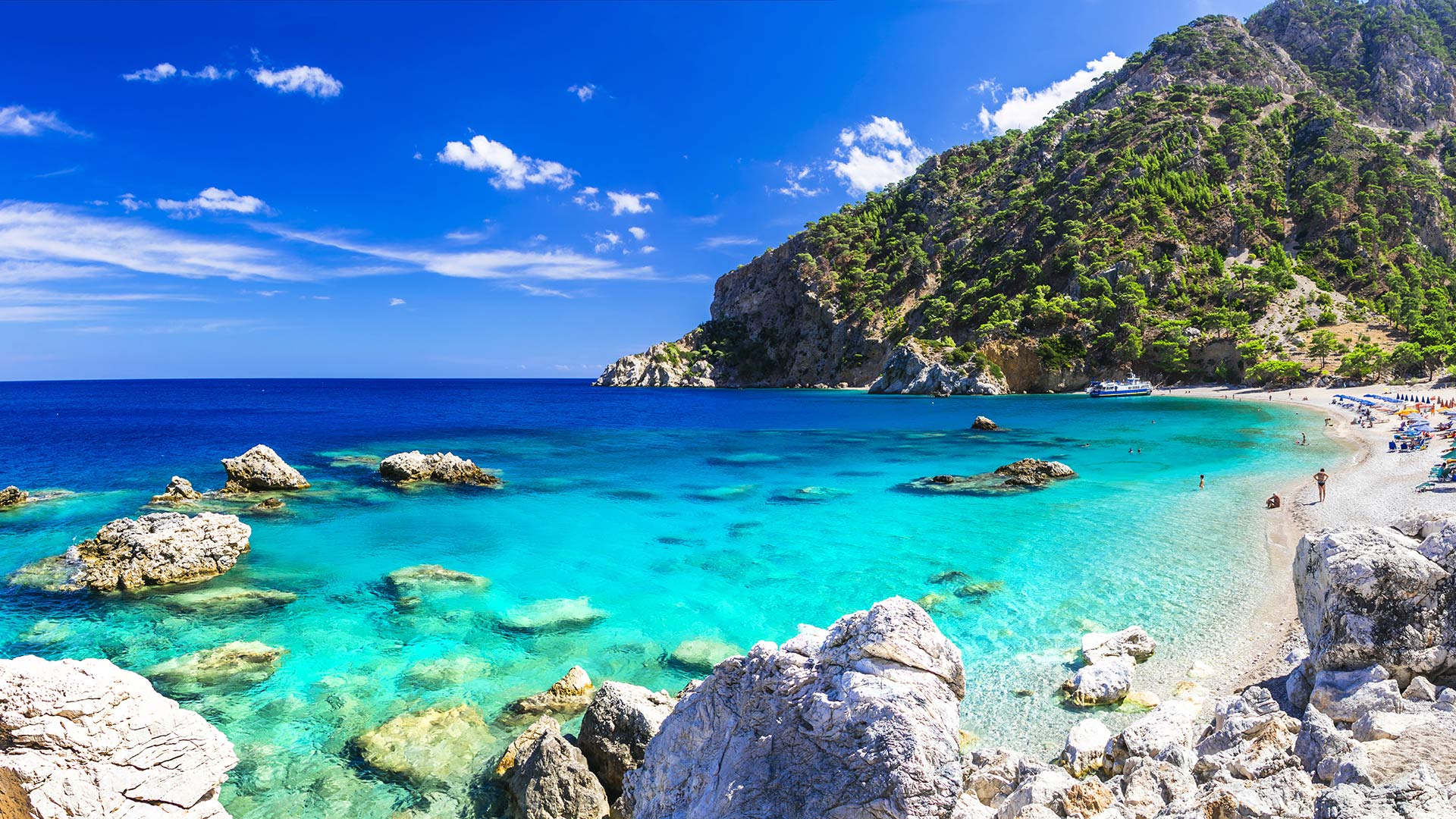 Het helder-blauwe water van Apella Beach is een waar bezienswaardigheid op Karpathos